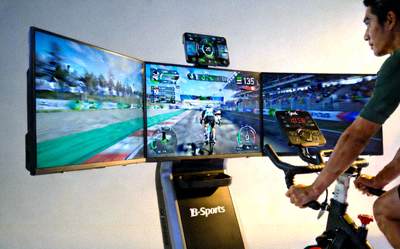 B-Sports 联网动感单车，用户正在骑行，前方大屏显示虚拟竞赛场景