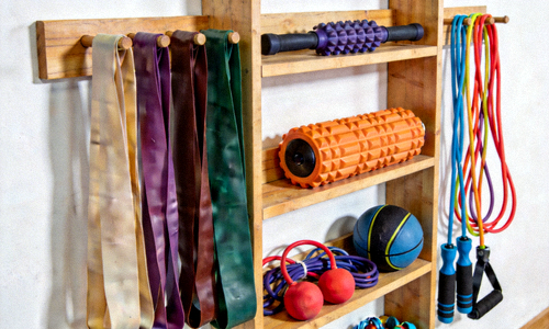 各种颜色的弹力带、按摩滚筒、跳绳等小工具整齐摆放在架子上